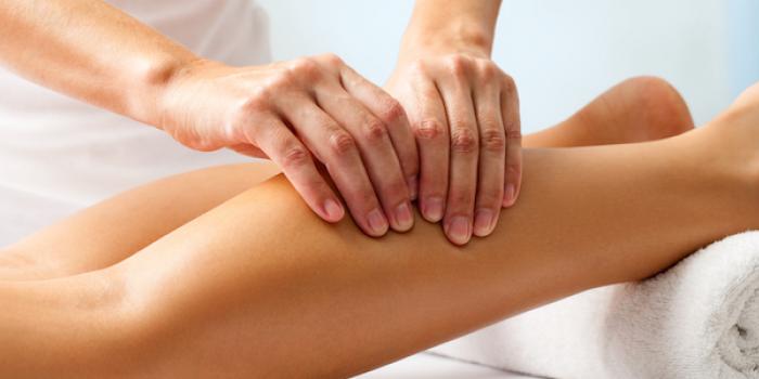 a female therapist massaging female patient's legs