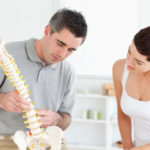 chiropractor and patient looking at the spine model