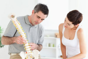 chiropractor and patient looking at the spine model