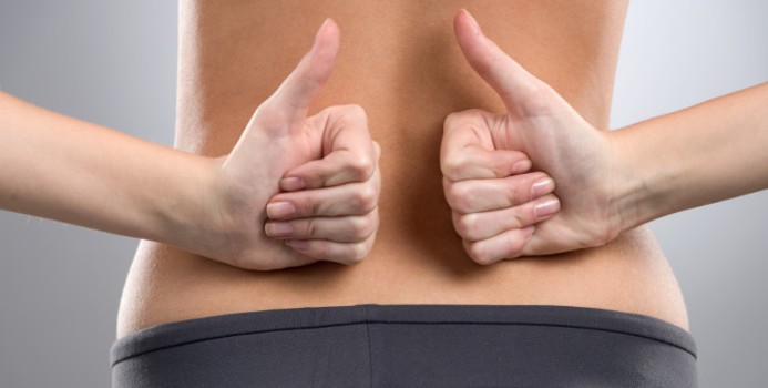 a woman holding her hands with thumbs up on her lower back