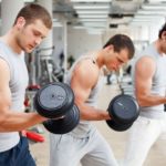 three men lifting weights in the gym