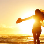 woman at the summer beach spreads her hands wide