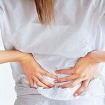 woman pressing her lower back with her hands