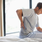 man with back pain sitting on his bed