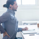 man with back pain sitting at his desk