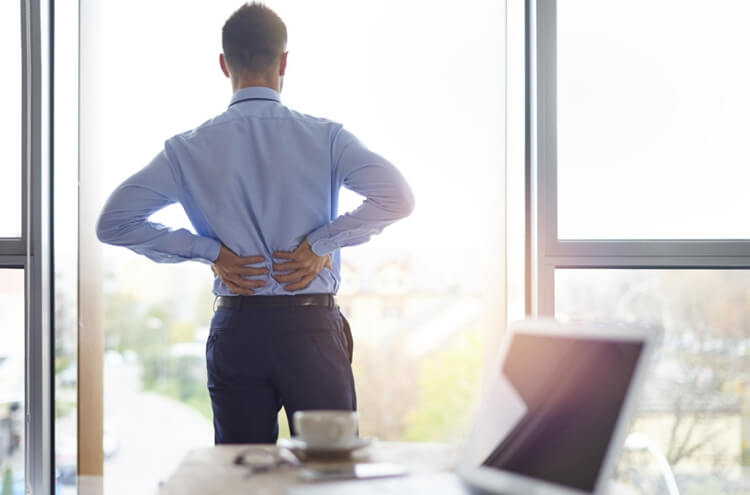 man with lower back pain in his office