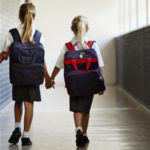 two girls carrying school backpacks