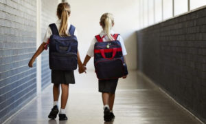 two girls carrying school backpacks