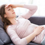 a woman lying on the couch with a headache