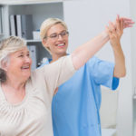 happy elderly woman and physiotherapist